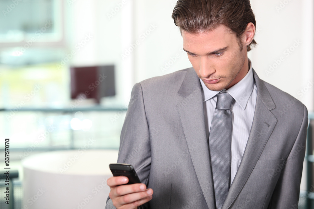 Male executive checking messages on cellphone Male executive checking messages on cellphone