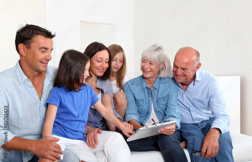 3-generation family sitting in couch with electronic tablet 3-generation family sitting in couch with electronic tablet