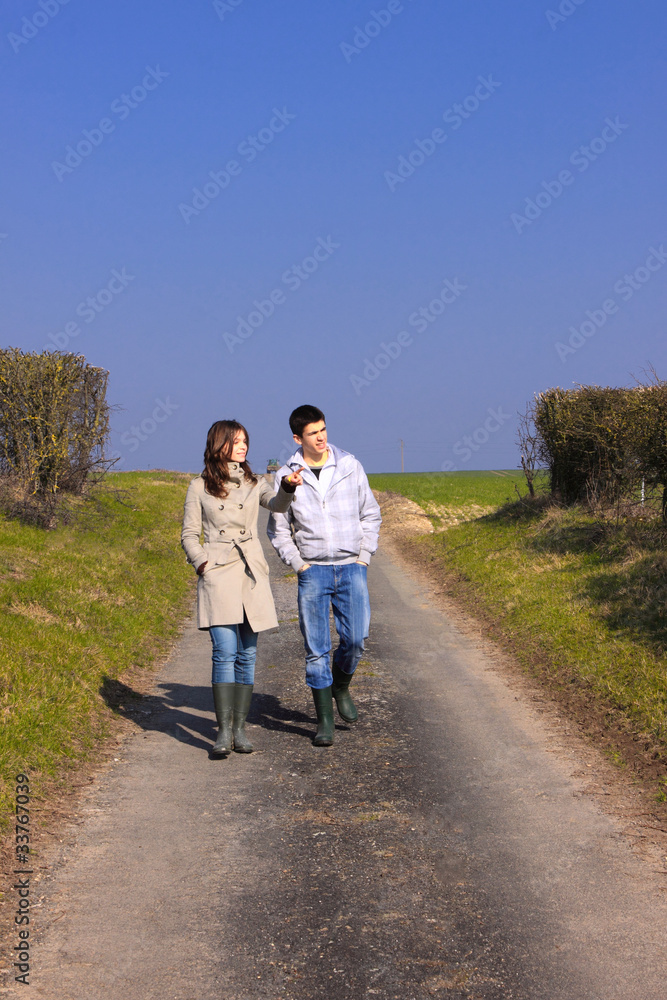 Couple of young people walking in the campaign in spring Couple of young people walking in the campaign in spring