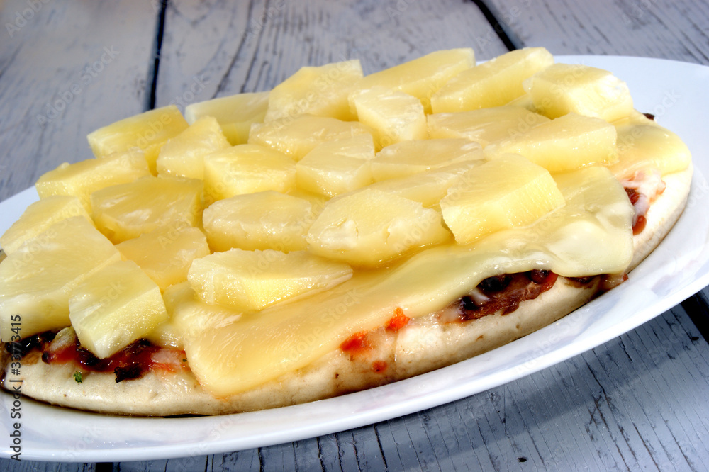 Pizza mit Käse und Ananas auf einem weißen Teller Pizza mit Käse und Ananas auf einem weißen Teller