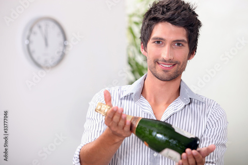 Man offering a bottle of champagne at five minutes to midnight photo