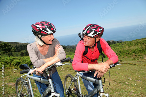 Fototapeta Naklejka Na Ścianę i Meble -  Senior couple riding mountain bikes in natural landscape