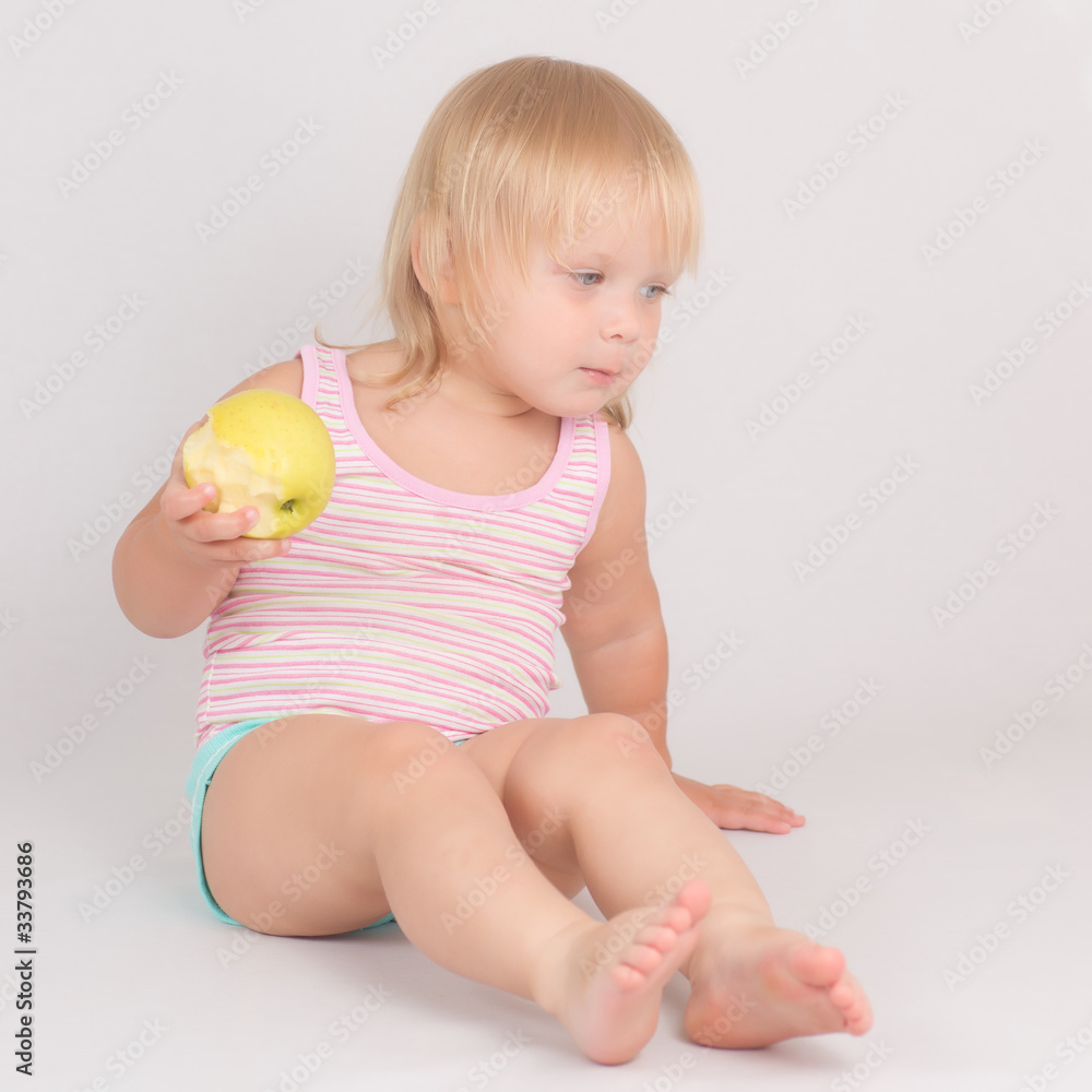 Adorable toddler girl eat green fresh apple sitting on white Adorable toddler girl eat green fresh apple sitting on white
