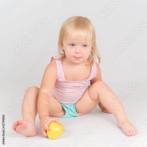 Adorable toddler girl eat green fresh apple sitting on white