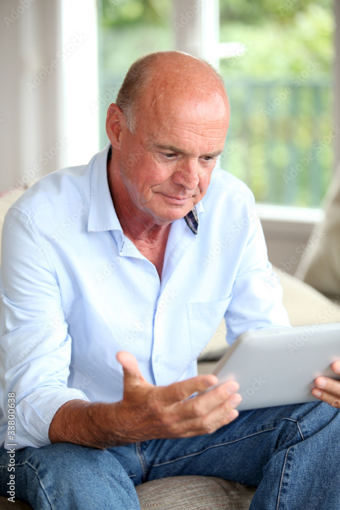 Senior man using electronic tablet at home Senior man using electronic tablet at home
