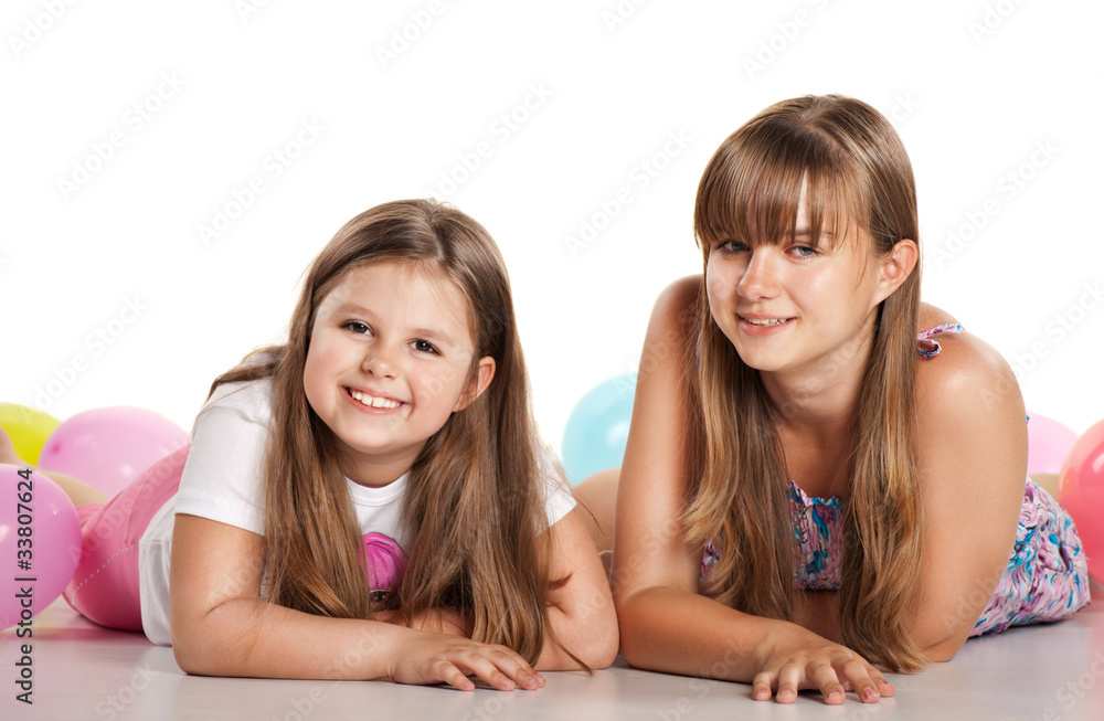 Two sisters lying on the floor with balloons Two sisters lying on the floor with balloons