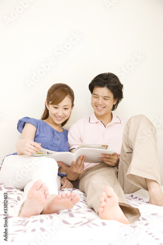 ベッドの上で雑誌を読む男女