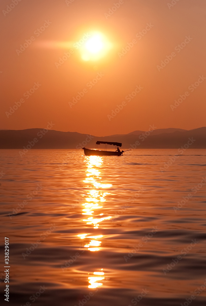 Fishermen crossing a lake at sunset