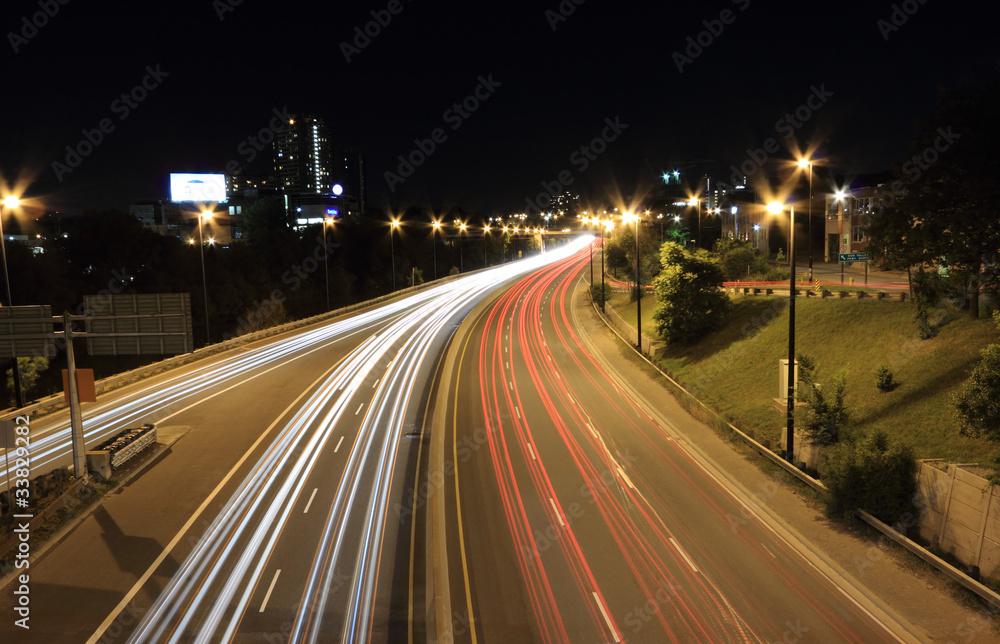 Moving vehicles create light trails along a highway at night