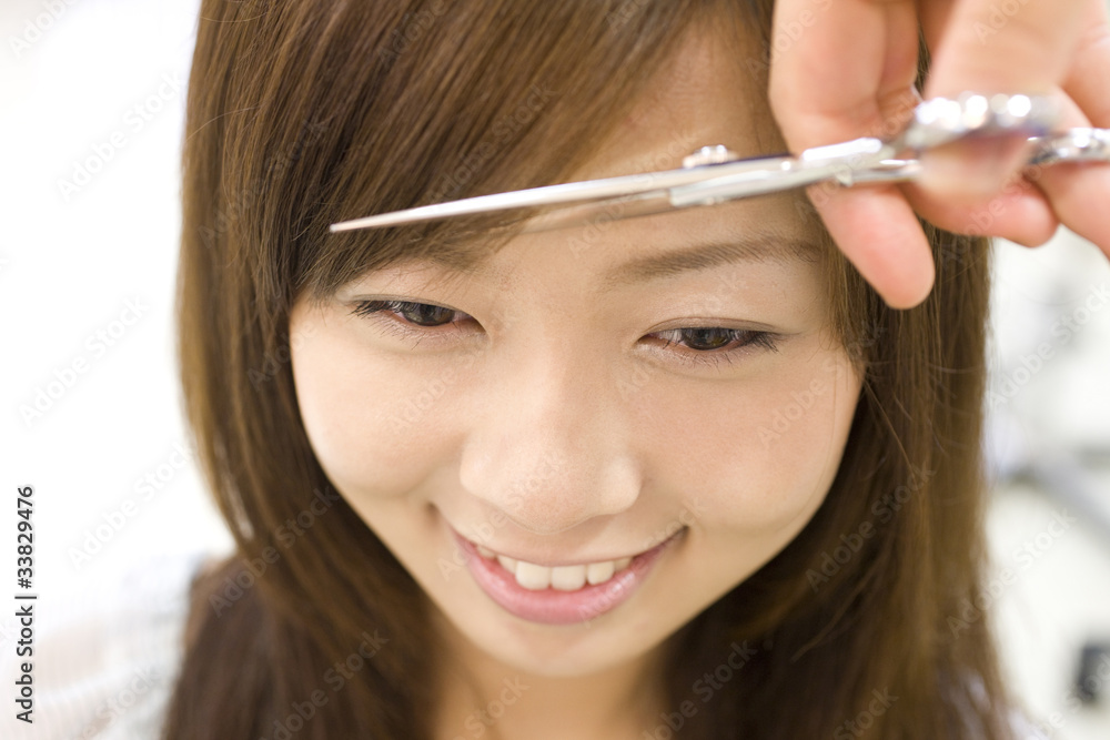 美容師に前髪を切ってもらう女性