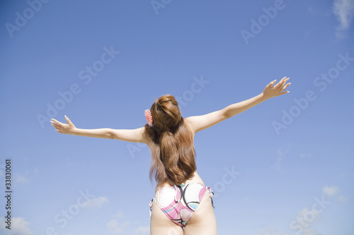Bild auf Leinwand 浜辺で両手を広げてリラックスしている水着姿の女性