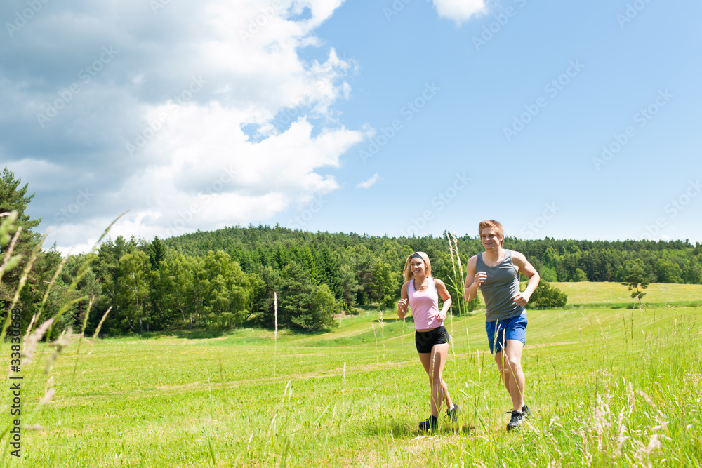 Sportive young couple jogging meadows sunny summer