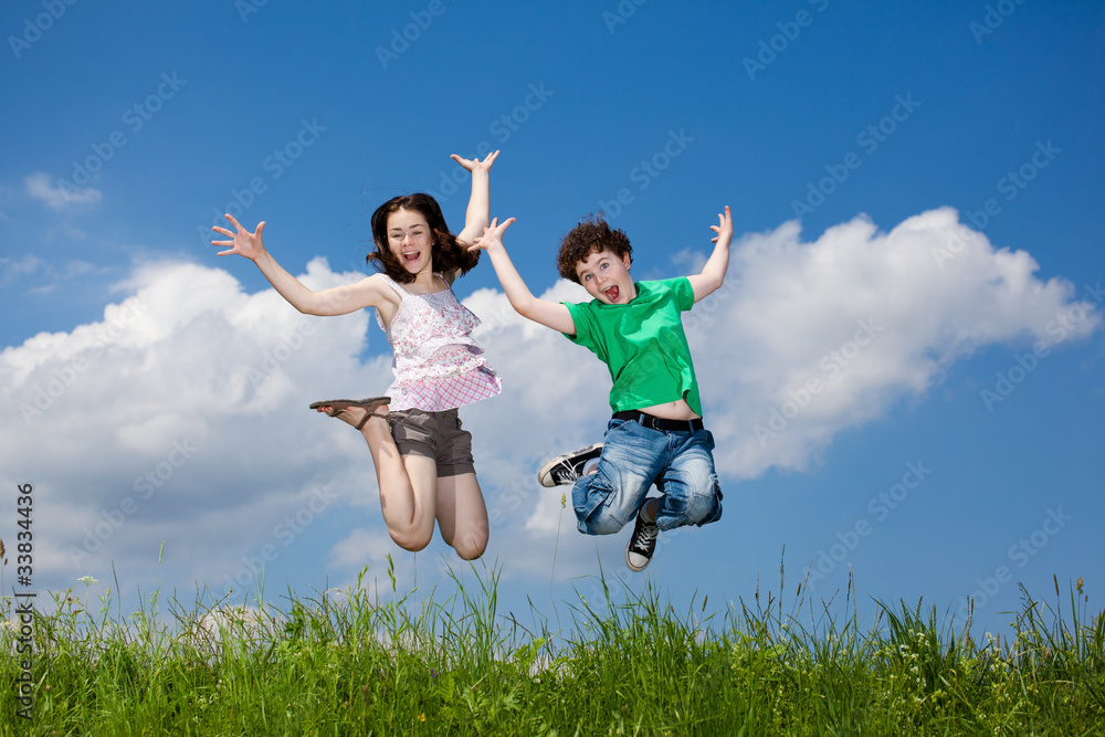Girl and boy jumping, running against blue sky Girl and boy jumping, running against blue sky