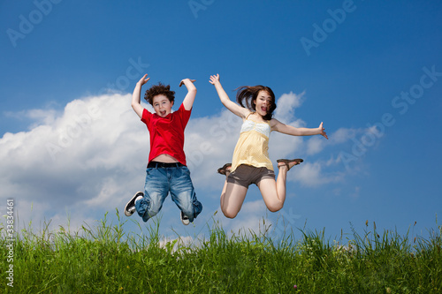 Girl and boy jumping  running against blue sky