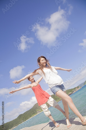 海辺の防波堤を歩く女性2人