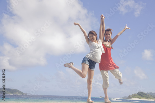 海辺に立って両手を上げる女性2人