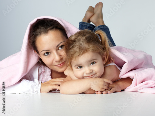 Young mother and daughter huggle together under a blanket photo