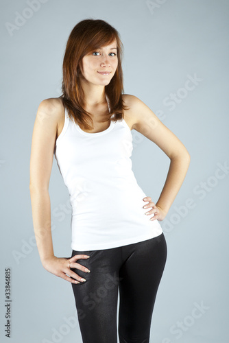 The young long-haired girl in a white vest on a grey background