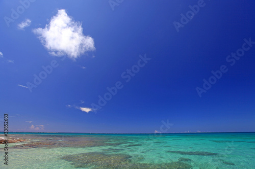 水納島の澄んだサンゴ礁の海と青い空に浮かぶ白い雲