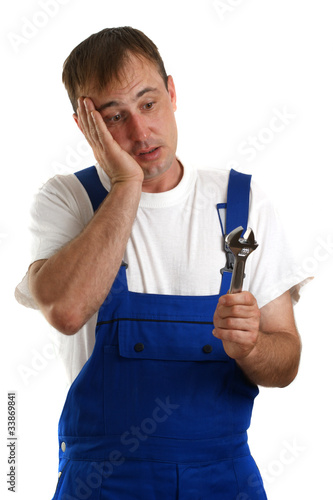 Handwerker mit blauer Latzhose hält einen Verstellschlüssel