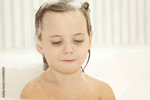 cute baby is washing her hair in bath