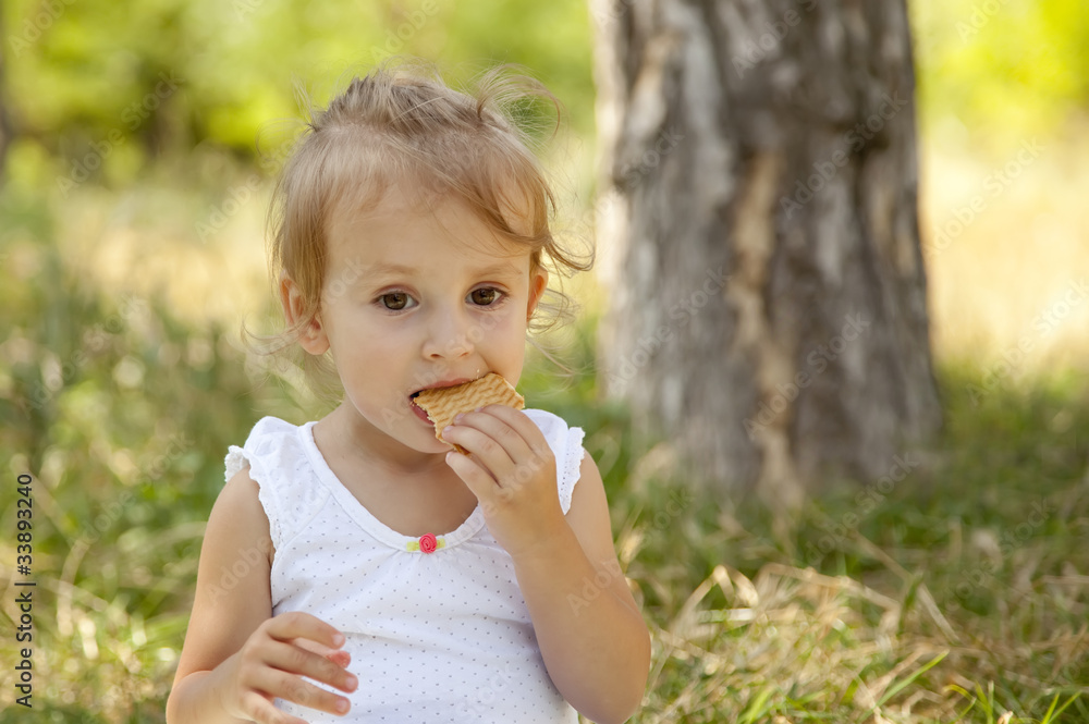 Little girl eating cracker in the park. Little girl eating cracker in the park.