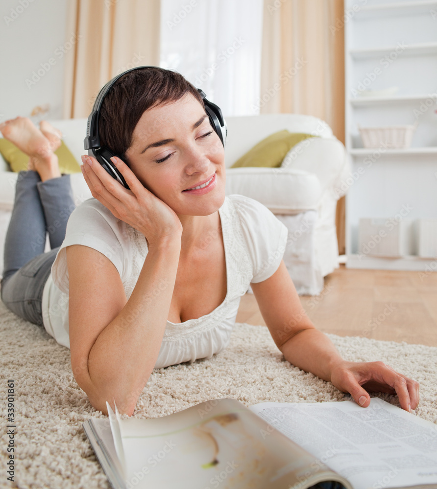 Portrait of a delighted woman with a magazine enjoying some musi Portrait of a delighted woman with a magazine enjoying some musi