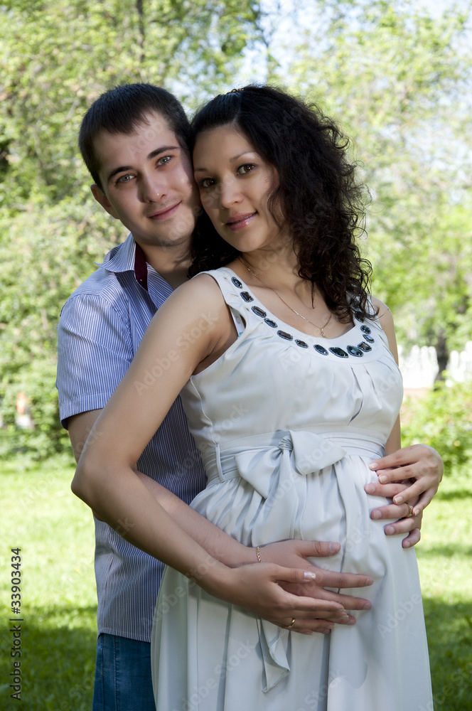 Man and a pregnant woman hugging in the park Man and a pregnant woman hugging in the park