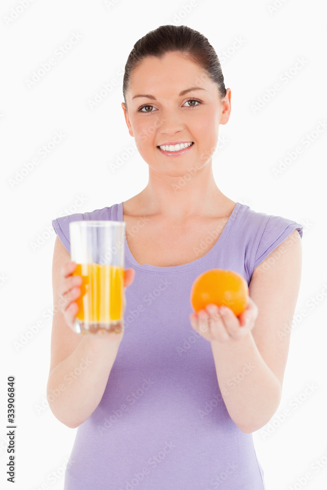 Portrait of an attractive woman holding an orange and a glass of Portrait of an attractive woman holding an orange and a glass of