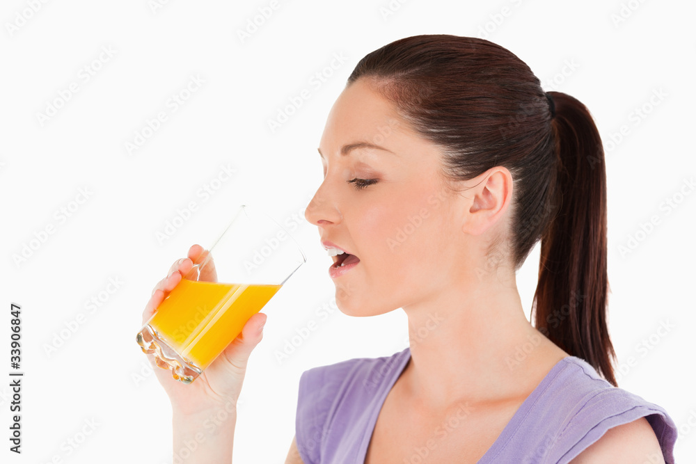 Beautiful woman drinking a glass of orange juice while standing Beautiful woman drinking a glass of orange juice while standing