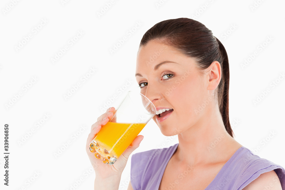 Attractive woman drinking a glass of orange juice while standing Attractive woman drinking a glass of orange juice while standing