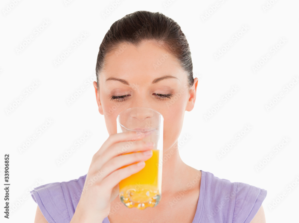 Good looking woman drinking a glass of orange juice while standi Good looking woman drinking a glass of orange juice while standi
