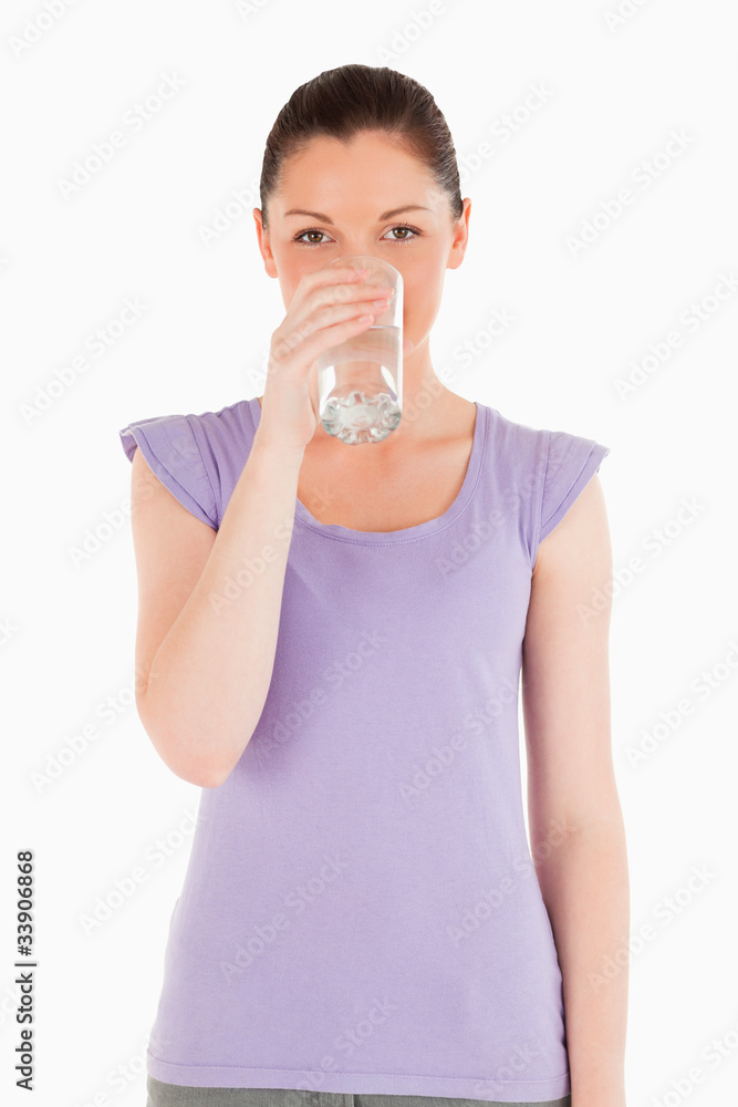 Charming woman drinking a glass of water while standing Charming woman drinking a glass of water while standing