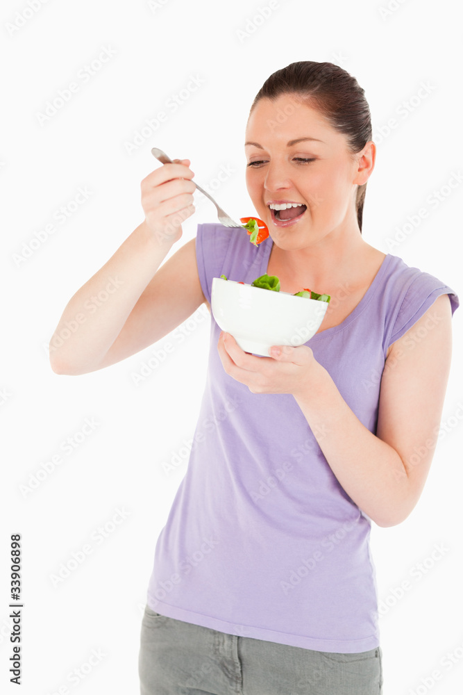 Beautiful woman eating a bowl of salad while standing Beautiful woman eating a bowl of salad while standing