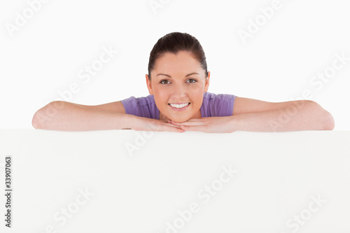 Good looking woman posing behind a billboard while standing