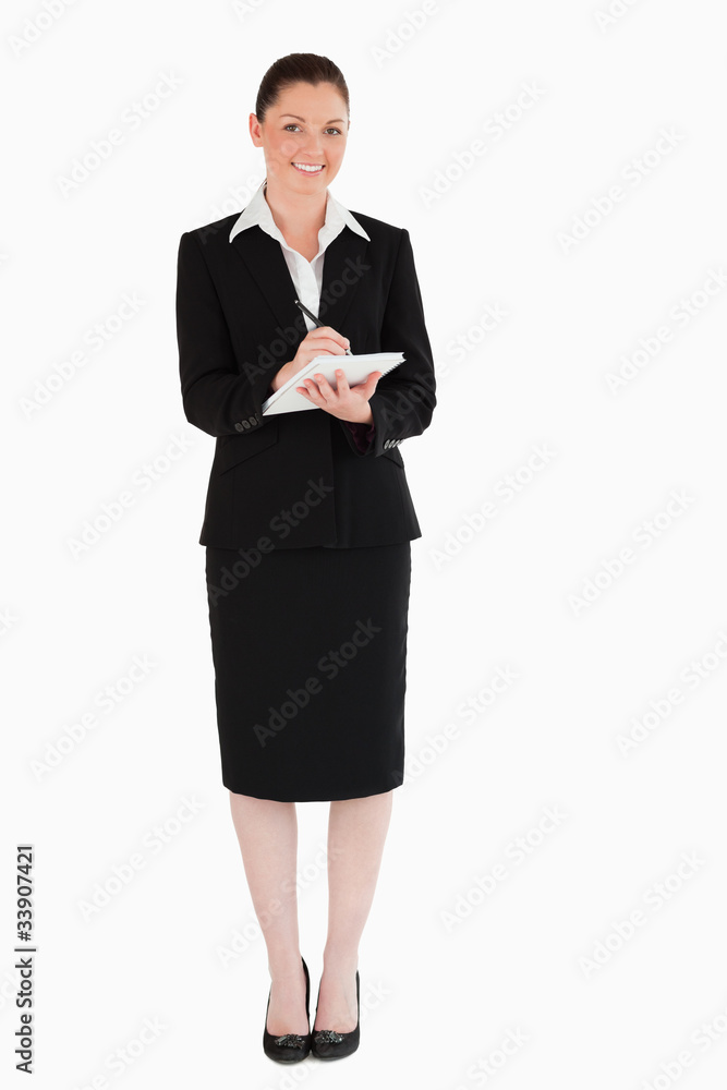 Charming woman in suit writing on a notebook Charming woman in suit writing on a notebook
