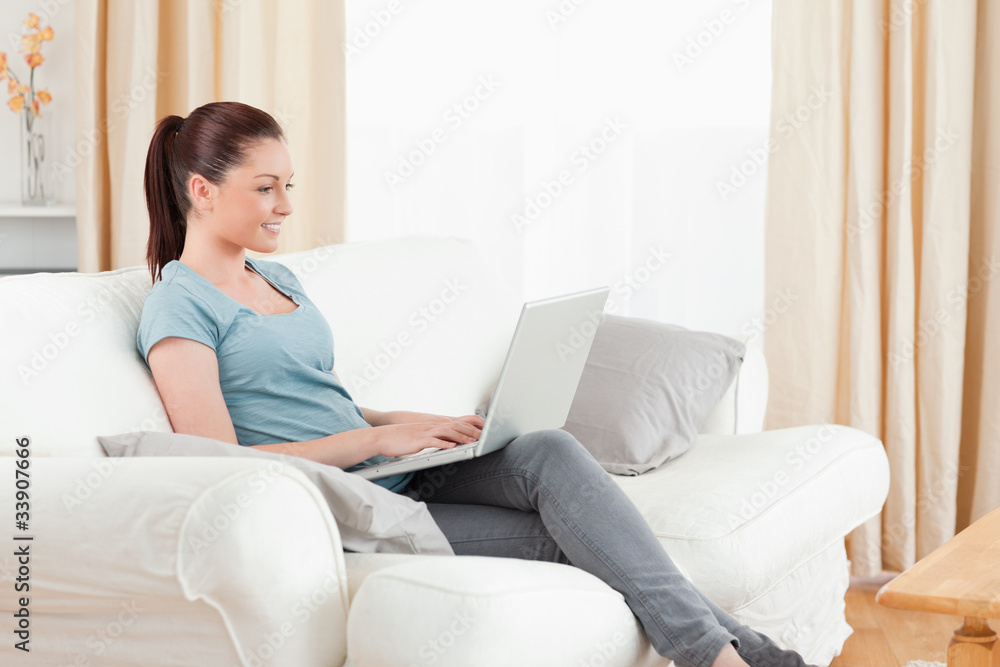 Attractive woman relaxing with her laptop while sitting on a sof Attractive woman relaxing with her laptop while sitting on a sof