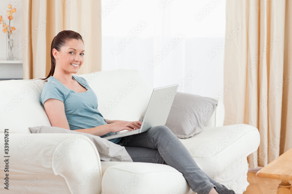 Good looking woman relaxing with her laptop while sitting on a s Good looking woman relaxing with her laptop while sitting on a s