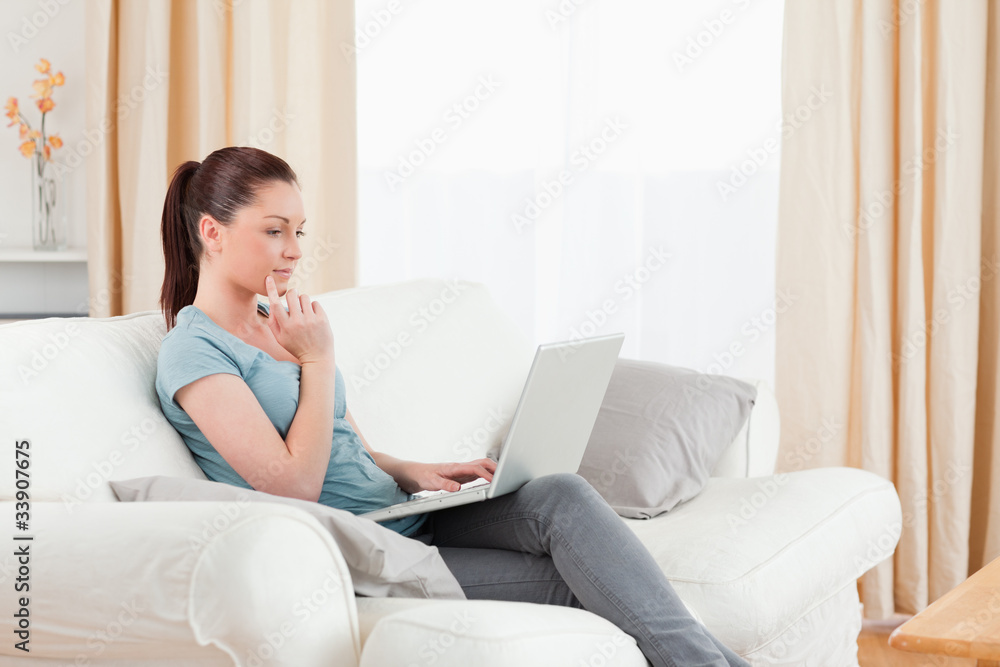 Beautiful woman relaxing with her laptop while sitting on a sofa Beautiful woman relaxing with her laptop while sitting on a sofa