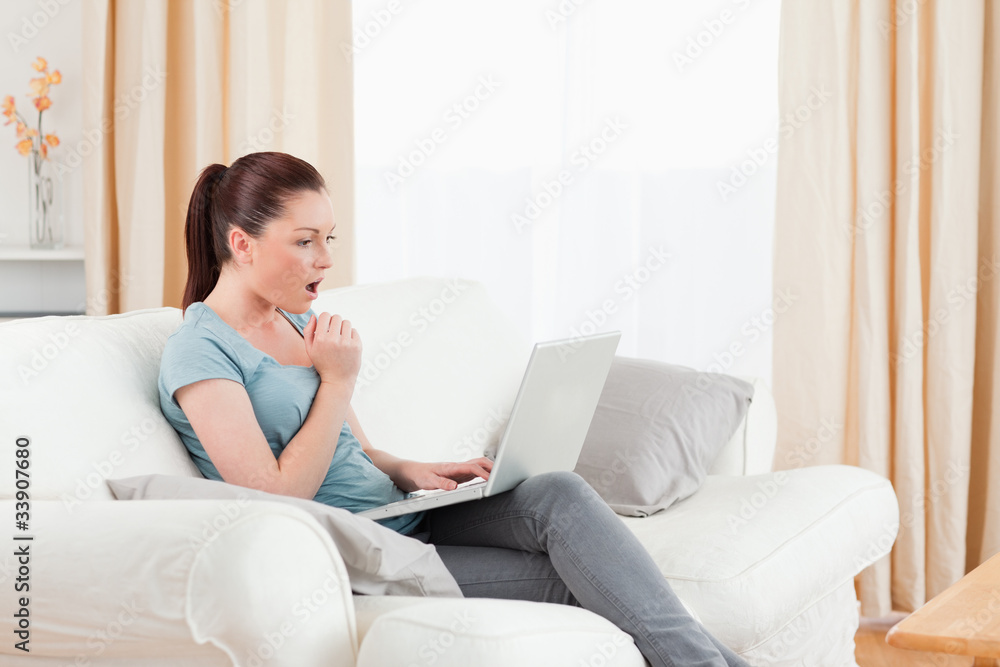Surprised woman gambling with her computer while sitting on a so Surprised woman gambling with her computer while sitting on a so