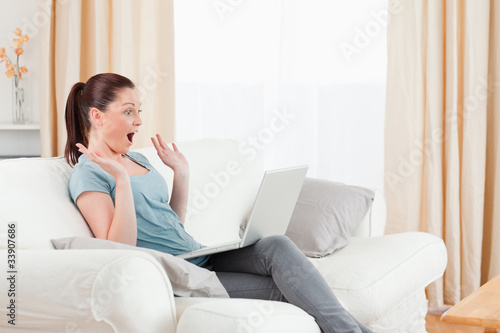 Joyful woman gambling with her computer while sitting on a sofa