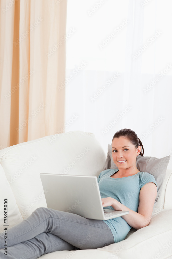 Gorgeous woman relaxing with her laptop while lying on a sofa Gorgeous woman relaxing with her laptop while lying on a sofa