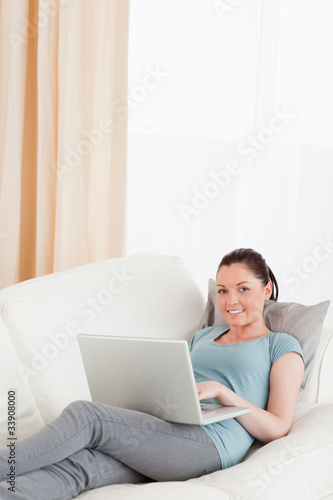 Gorgeous woman relaxing with her laptop while lying on a sofa