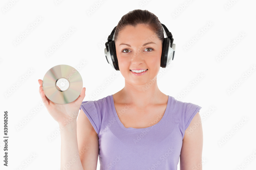 Good looking woman with headphones holding a CD while standing Good looking woman with headphones holding a CD while standing