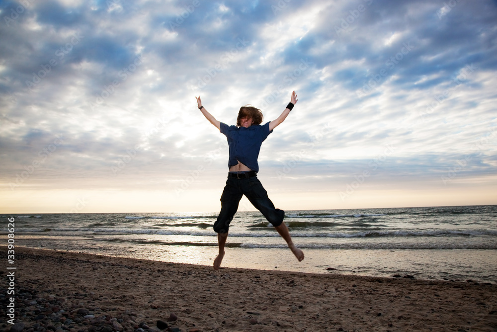 Happy young man jumping on the beach