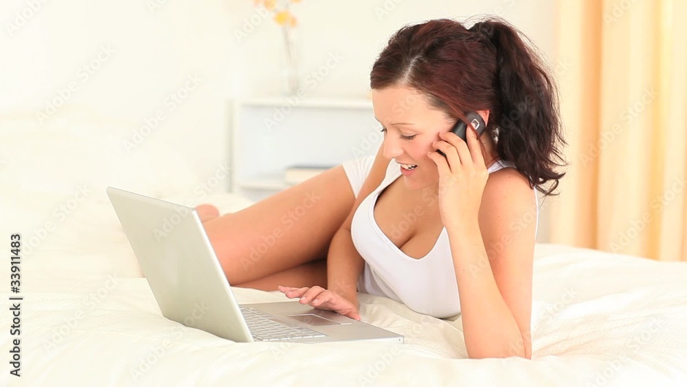 Active woman using her laptop while speaking on the phone Active woman using her laptop while speaking on the phone