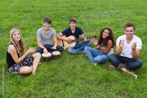 junge leute sitzen im gras und musizieren