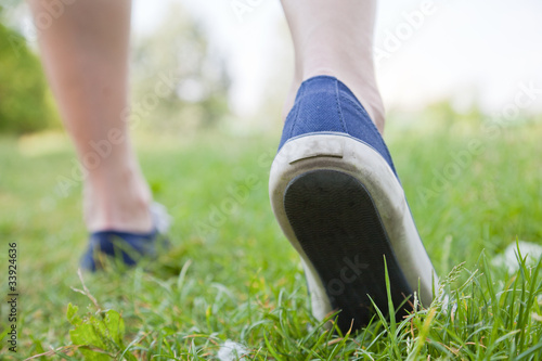 Woman walking on green grass in sport shoes