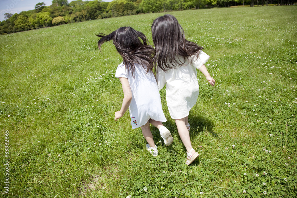 草原を走る女の子2人の後ろ姿 Stock Photo Adobe Stock