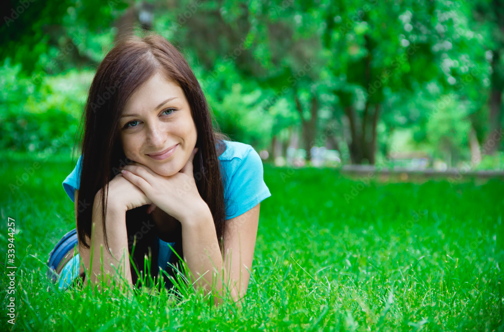 Portrait of a happy young woman lying on grass Portrait of a happy young woman lying on grass